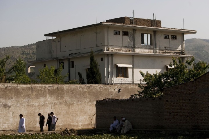 Image: People walk past Osama Bin Laden's compound in Abottabad, Pakistan, in 2011.