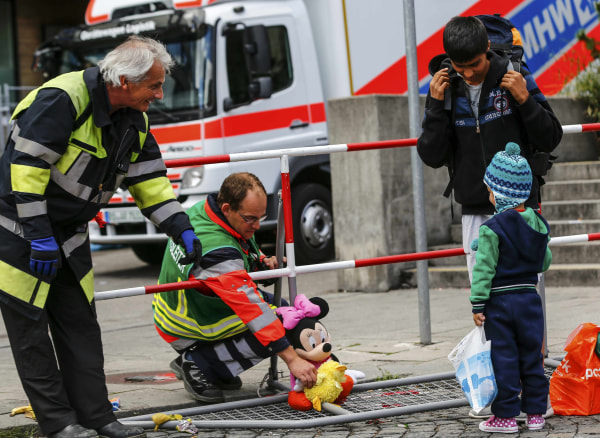 Image: Firefighters chat with migrants who arrived by train to the main railway station in Munich