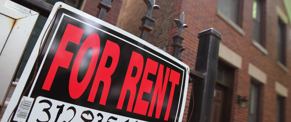 Image: A "For Rent" sign stands in front of a house