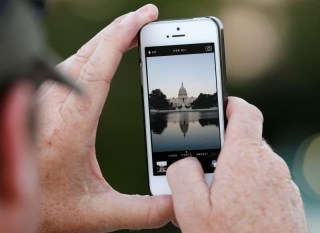 A man takes a photo of the U.S. Capitol, on the eve of a potential federal government shutdown, in Washington
