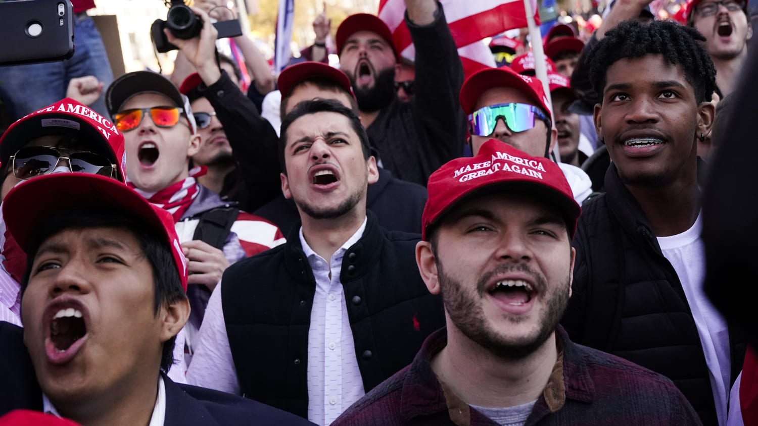 A photoshows a crowd of unmasked Trump supporters shouting