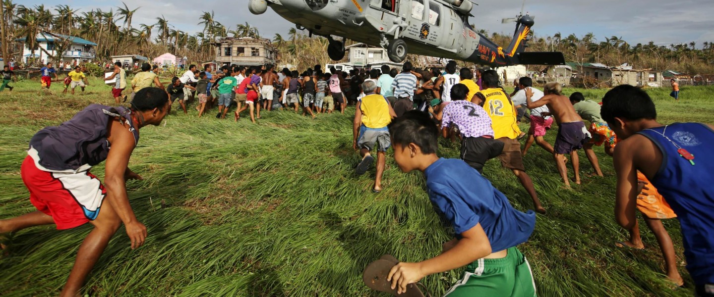 Image: Filipino typhoon victims rush to get relief goods from a US Navy Sea Hawk helicopter 