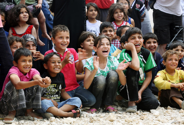 Image: Syrian refugee children smile while watching members of "Clowns Without Borders"