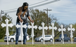 Image: Sheree Rumph of San Antonio prays over two of the 26 crosses erected in memory of the people killed