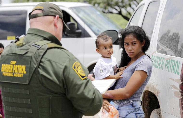 Image: A mother holds her 1-year-old child as they surrender to Border Patrol