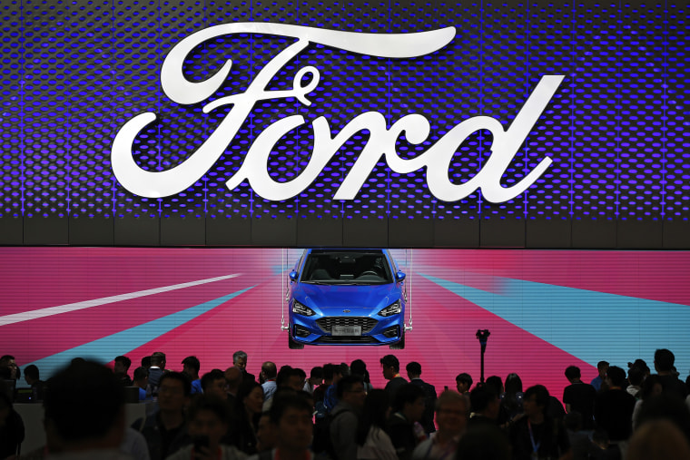 Visitors and journalists crowd near a Ford Focus on display at the Ford exhibit during the media day for the China Auto Show in Beijing on April 25, 2018.