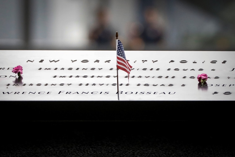 Image: Flowers and a flag are left on names on the National 9/11 Memorial during ceremonies marking the 17th anniversary of the September 11, 2001 attacks on the World Trade Center, at the National 9/11 Memorial and Museum in New York
