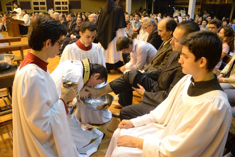 Priest Carlos Urrutigoity kisses the feet of the faithful.
