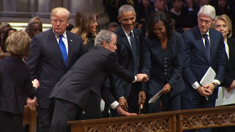 George W. Bush gives Michelle Obama a mint or cough drop at George H.W. Bush's funeral