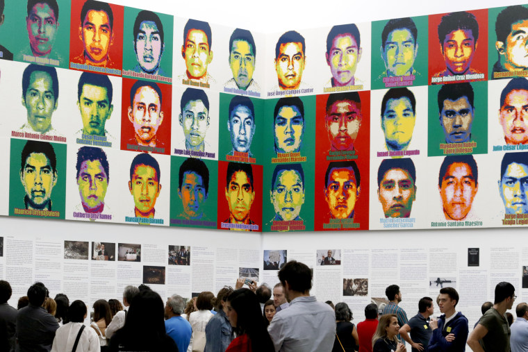 Image: People stand under portraits of 43 college students as part of an art installation by Ai Weiwei at the Contemporary Art University Museum in Mexico City on April 13, 2019.