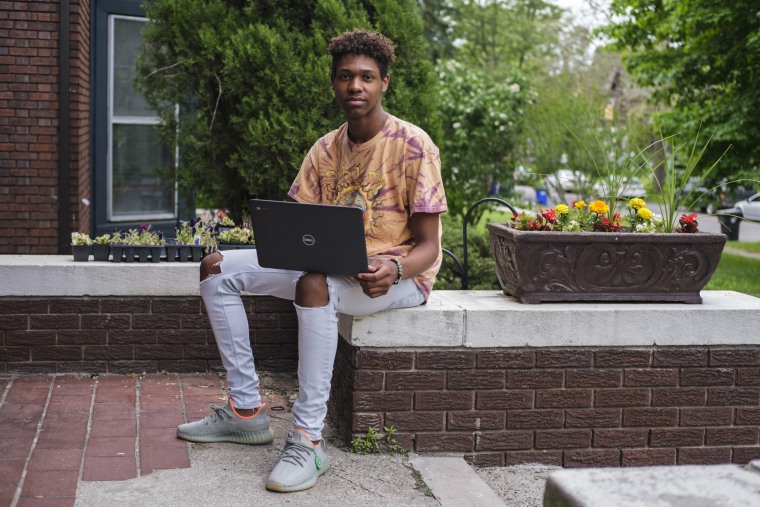 Xavier Prater, 17, a Grosse Pointe South High School student, with his laptop outside his father's home in Detroit.