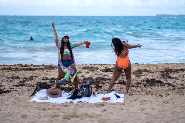 Image: A couple of tourists dance in the beach in the tourist zone of El Condado in San Juan, Puerto Rico on March 14, 2021.