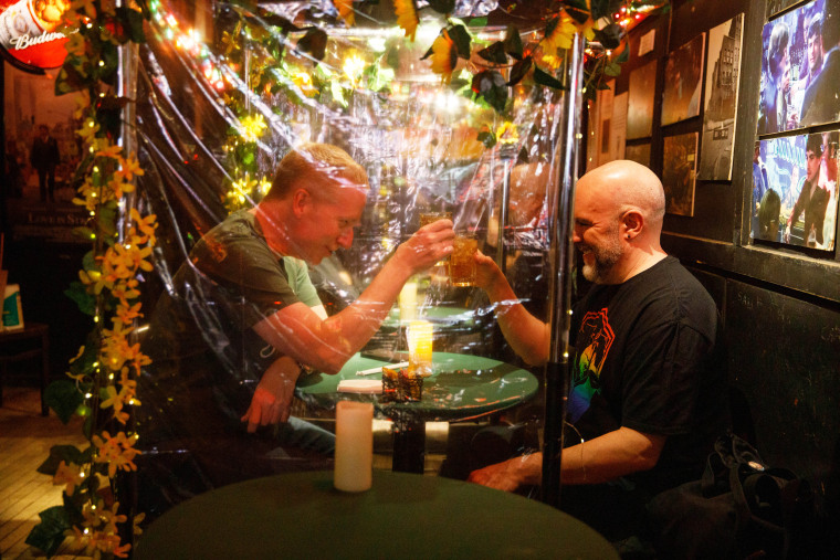 Brendan Byrnes and Stephen Cabral clink their drinks at Julius' in New York on March 19, 2021. Byrnes and Cabral got married at Julius' in 2015.