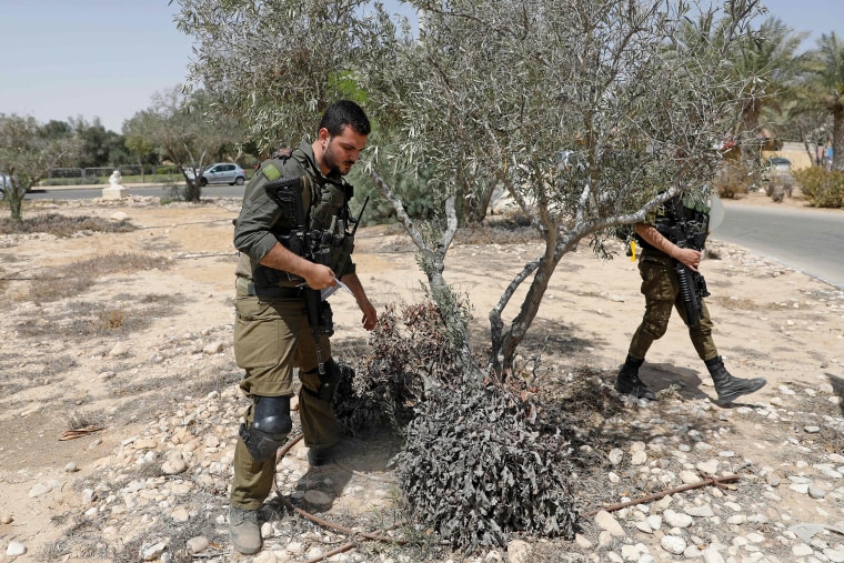 Image: Israeli soldiers search for debris after a missile launched from Syria landed in the vicinity of the Dimona nuclear site in Israel's southern Negev desert